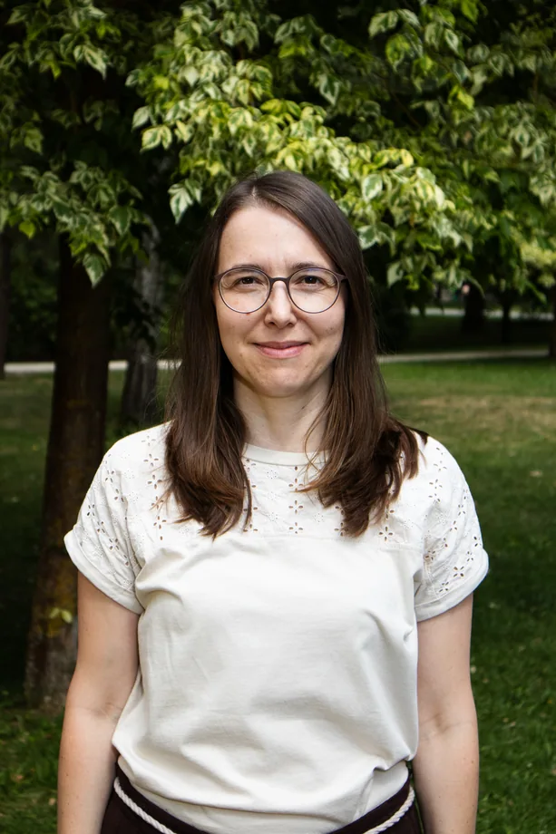 Portrét ženy v bílé halence před zelenými listy