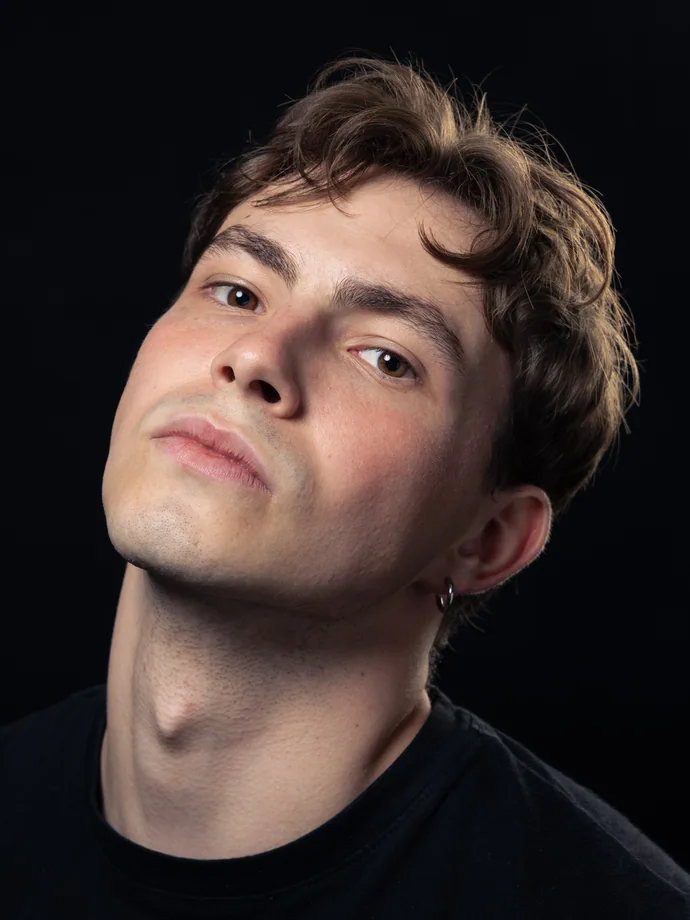 Studiový portrét muže s nakloněnou hlavou na tmavém pozadí