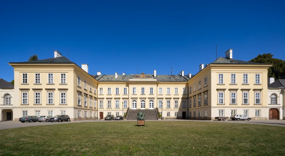 Symetrický pohled na zámecký areál pod modrou oblohou