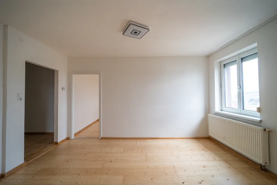 Prázdný světlý pokoj s dřevěnou podlahou a okny